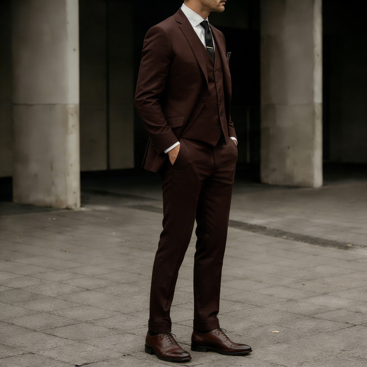 Side view of a man wearing a dark brown three-piece suit in formal styling