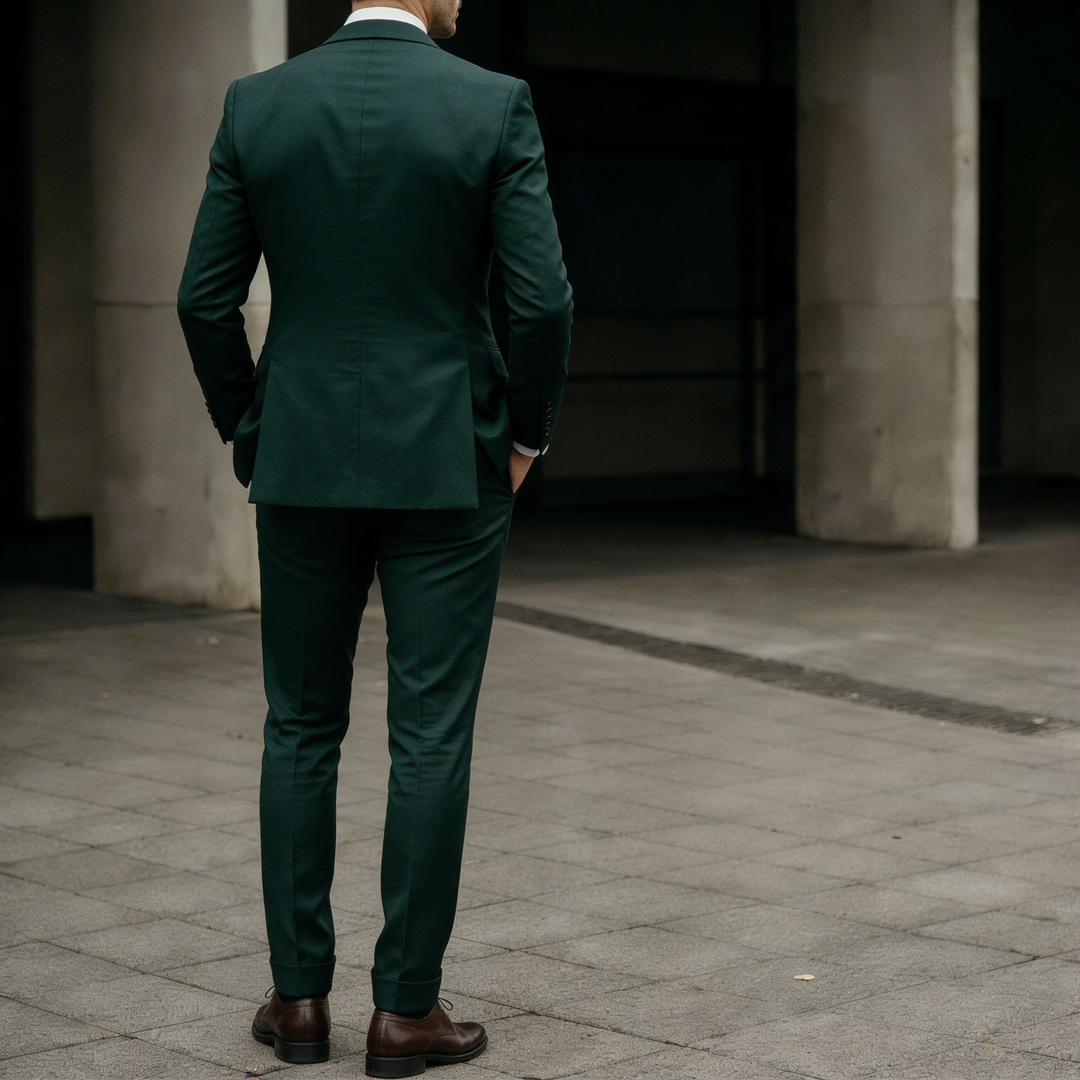 Back view of a man wearing a dark green three-piece suit in formal styling